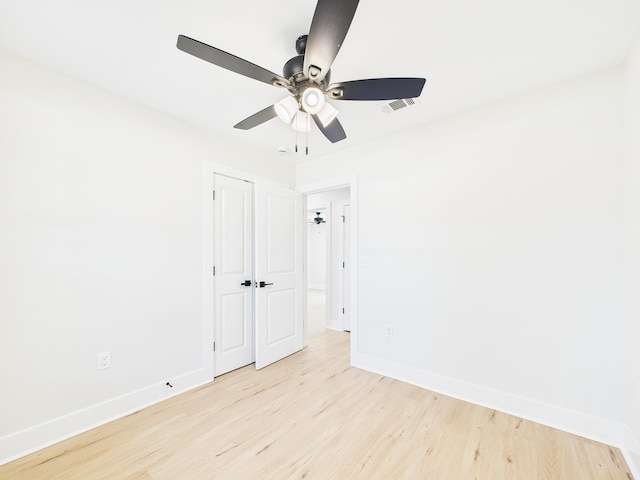 unfurnished room featuring baseboards, visible vents, light wood finished floors, and ceiling fan