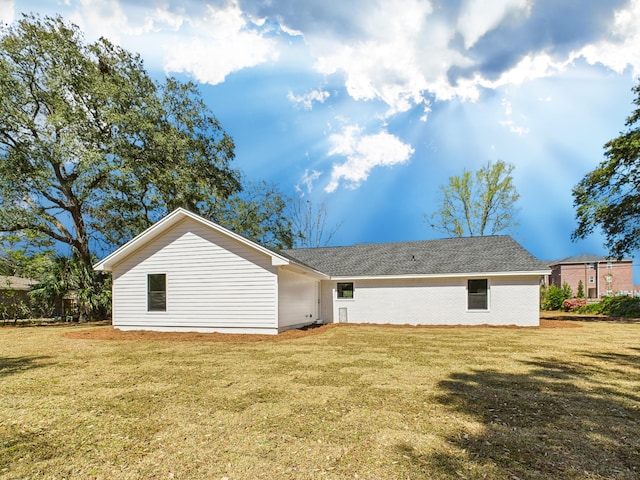 rear view of property with brick siding and a lawn