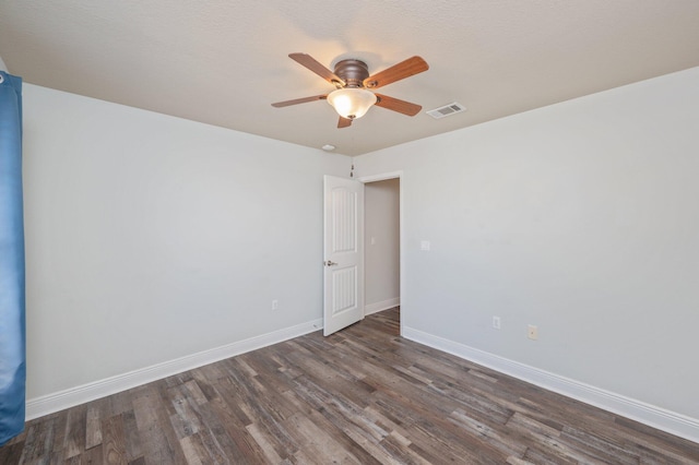 empty room featuring a ceiling fan, visible vents, baseboards, and wood finished floors