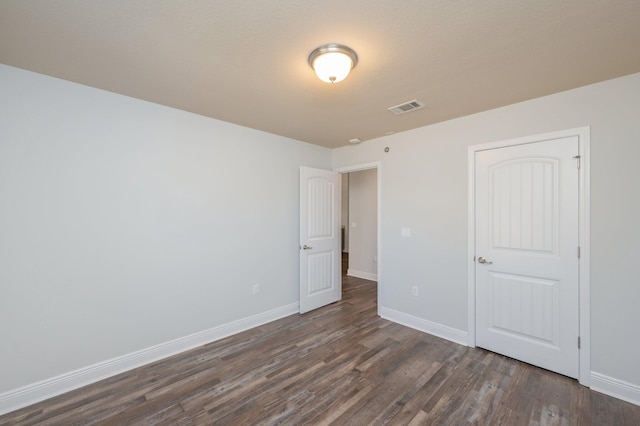 unfurnished bedroom featuring dark wood-style floors, visible vents, and baseboards