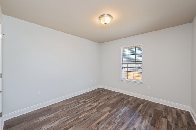 empty room featuring baseboards and dark wood-type flooring