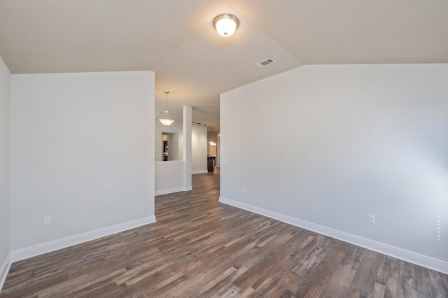 unfurnished room featuring dark wood-style floors, baseboards, visible vents, and vaulted ceiling