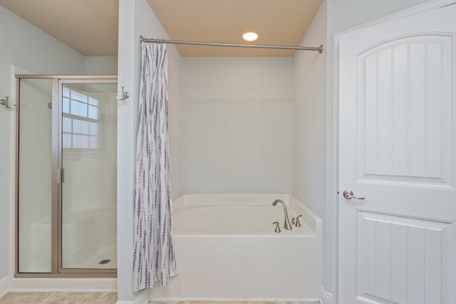 bathroom featuring a shower stall and a bath