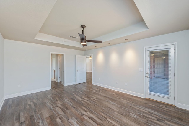 spare room with ceiling fan, baseboards, a raised ceiling, and wood finished floors