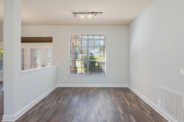 unfurnished dining area with dark wood-style flooring, visible vents, and baseboards