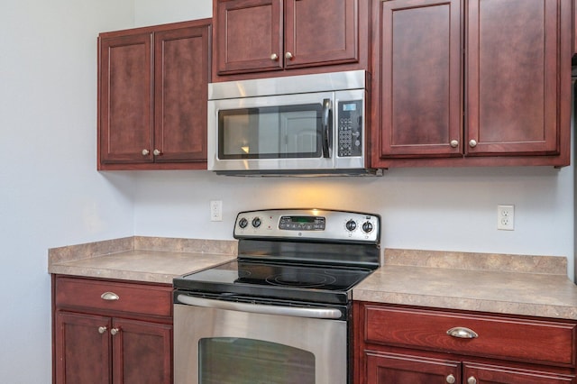 kitchen featuring stainless steel appliances, light countertops, and dark brown cabinets