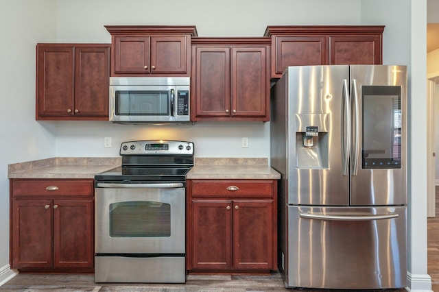 kitchen featuring appliances with stainless steel finishes, light countertops, and wood finished floors