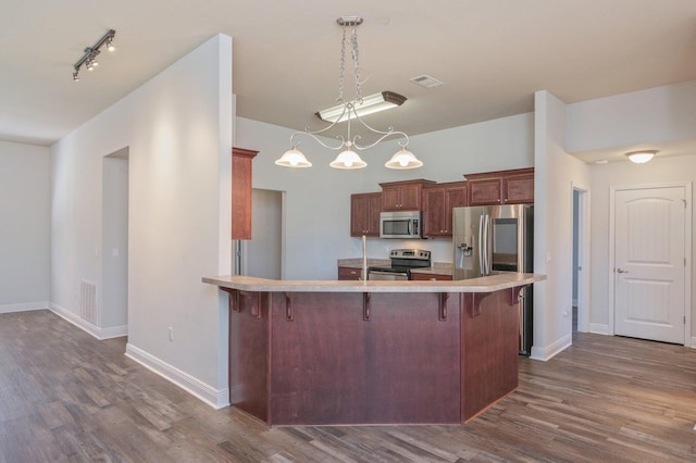 kitchen with visible vents, a breakfast bar area, dark wood-type flooring, stainless steel appliances, and light countertops