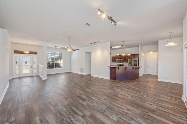 unfurnished living room with a ceiling fan, baseboards, visible vents, and dark wood-style flooring