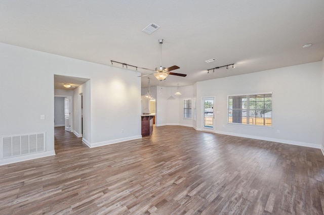 unfurnished living room with ceiling fan, wood finished floors, visible vents, and baseboards