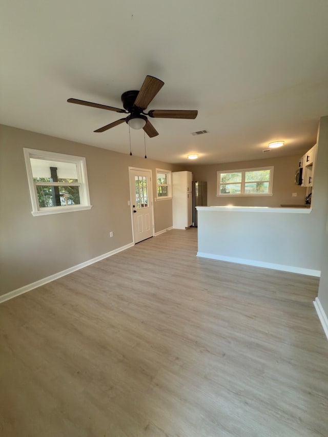 interior space featuring ceiling fan, visible vents, baseboards, and light wood-style flooring