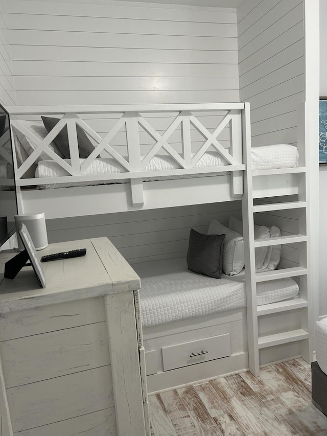 bedroom featuring wooden walls, a bar, and wood finished floors