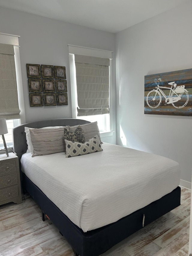 bedroom with baseboards, multiple windows, and wood finished floors