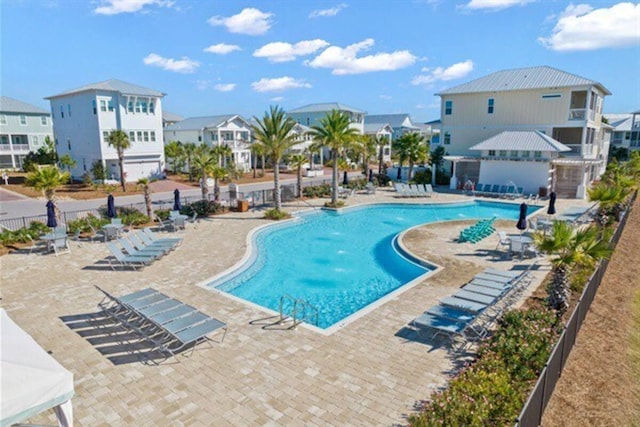 community pool with a patio area, a residential view, and fence