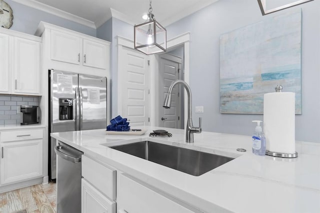 kitchen featuring ornamental molding, a sink, backsplash, white cabinetry, and stainless steel appliances