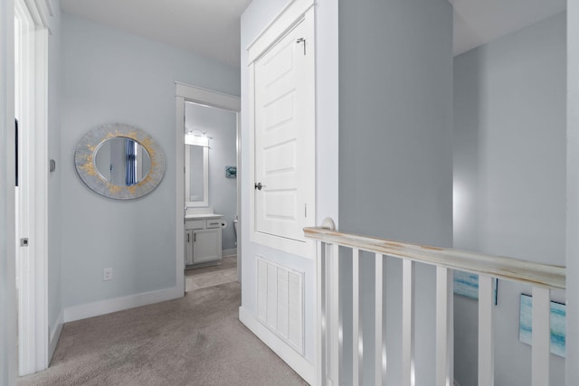 hallway with visible vents, carpet flooring, and baseboards