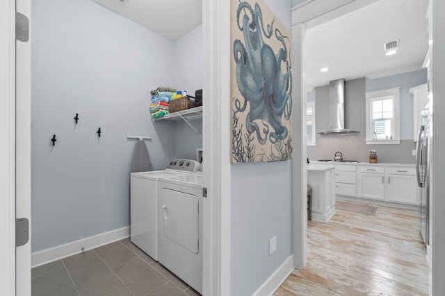 washroom featuring washer and dryer, visible vents, baseboards, and light wood-style flooring