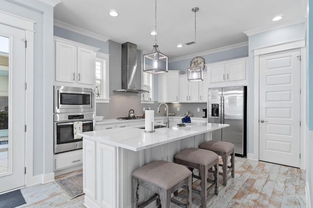 kitchen with ornamental molding, stainless steel appliances, wall chimney exhaust hood, and a sink