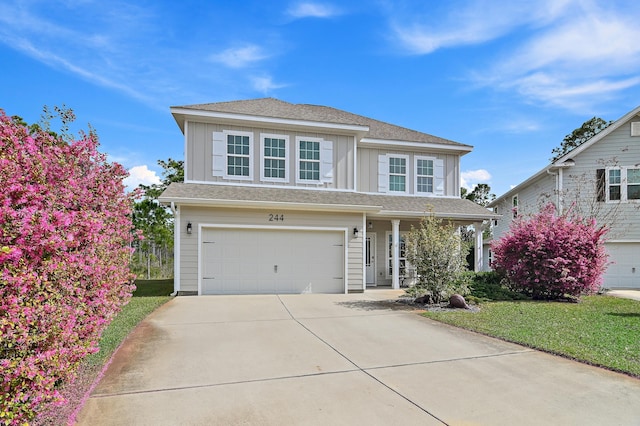 view of front facade with board and batten siding, a front yard, concrete driveway, and an attached garage