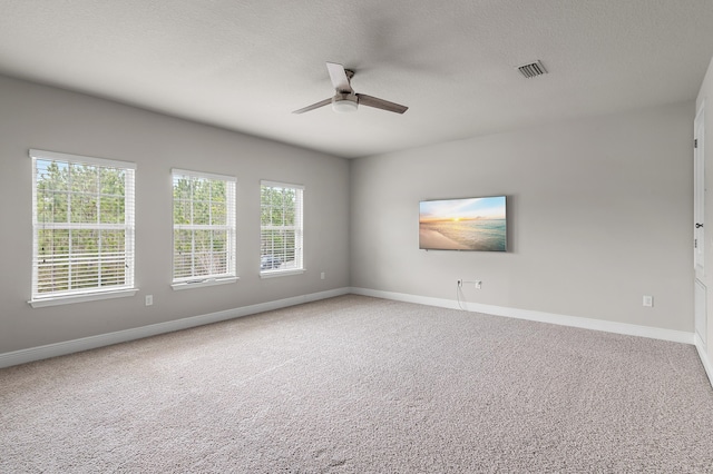 unfurnished room featuring a textured ceiling, baseboards, visible vents, and light colored carpet