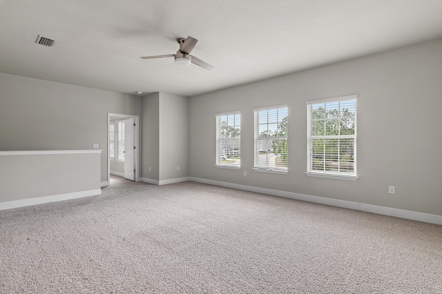 empty room with light carpet, a ceiling fan, visible vents, and baseboards