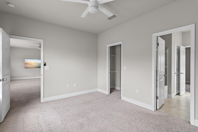 unfurnished bedroom with baseboards, a spacious closet, visible vents, and light colored carpet