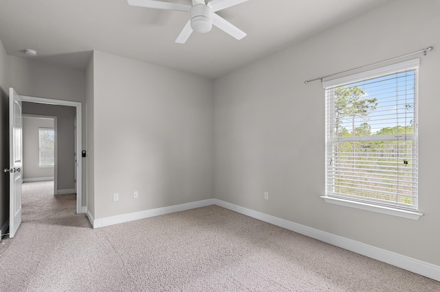 carpeted empty room with a ceiling fan and baseboards