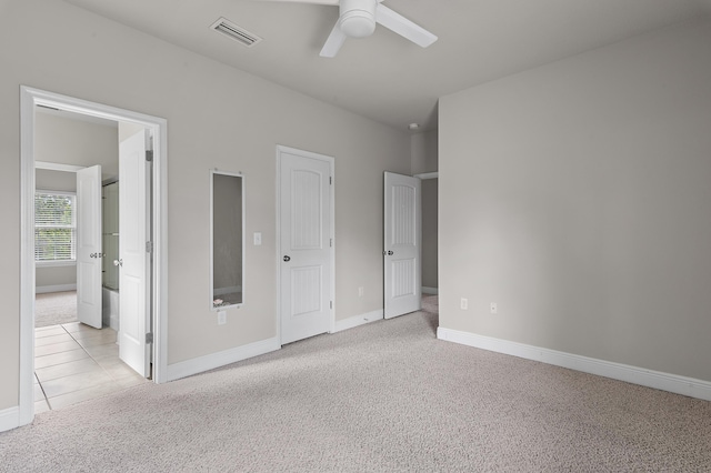 unfurnished bedroom with baseboards, ensuite bath, visible vents, and light colored carpet