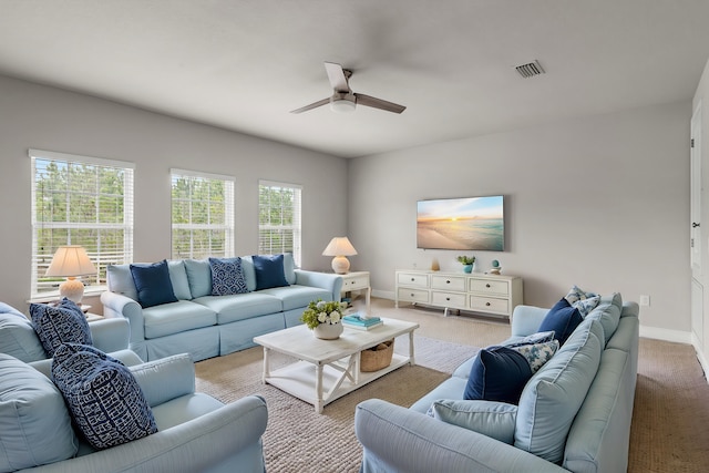 living area with light carpet, ceiling fan, visible vents, and baseboards