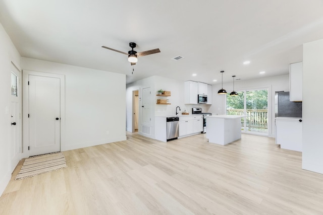 kitchen featuring stainless steel appliances, white cabinetry, light wood-style floors, a center island, and open shelves