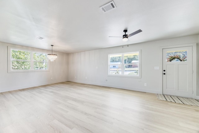 interior space with baseboards, visible vents, light wood finished floors, and ceiling fan with notable chandelier