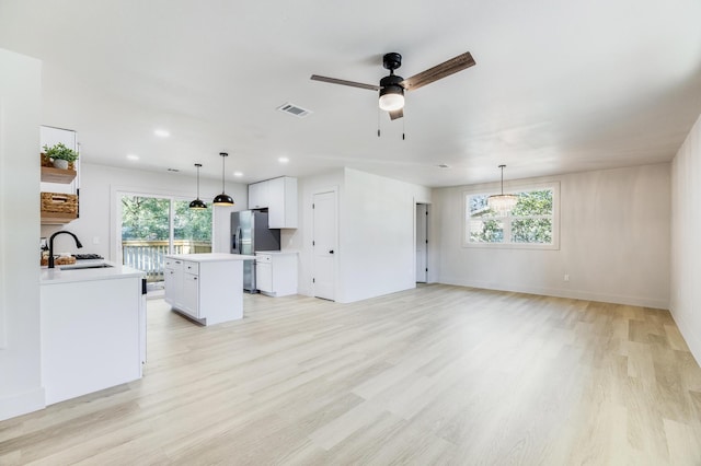 unfurnished living room featuring light wood-type flooring, a healthy amount of sunlight, and a sink