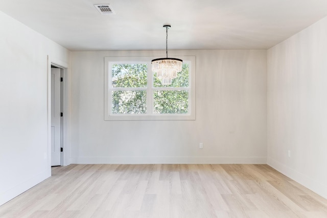 unfurnished room with light wood-type flooring, baseboards, visible vents, and a chandelier