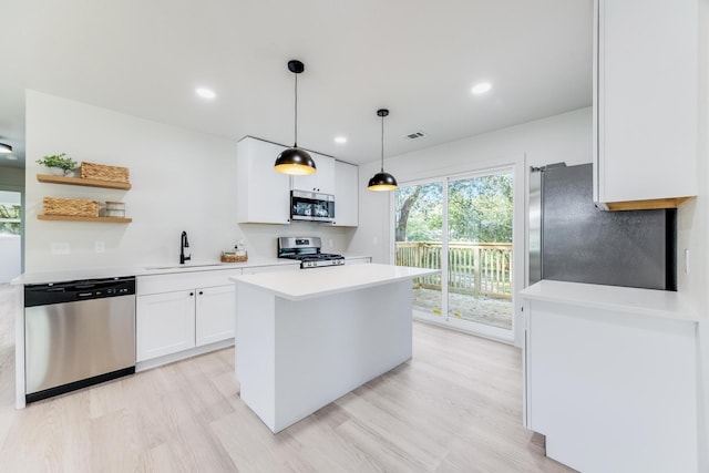 kitchen featuring a center island, light countertops, light wood-style flooring, appliances with stainless steel finishes, and white cabinetry