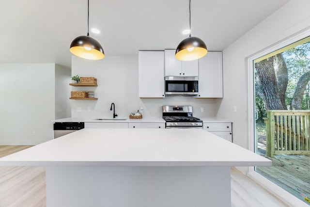 kitchen with open shelves, stainless steel appliances, light countertops, white cabinetry, and a sink