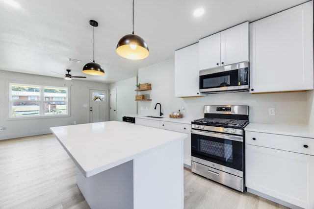 kitchen featuring open shelves, appliances with stainless steel finishes, light countertops, and a sink