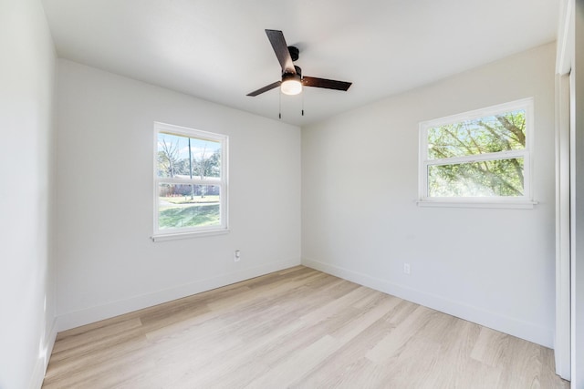 spare room featuring wood finished floors, a wealth of natural light, and baseboards