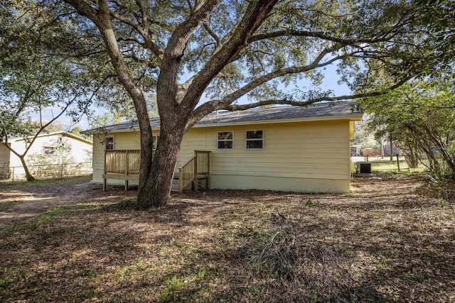 rear view of property with central air condition unit and fence