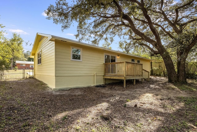 back of property with fence and a wooden deck