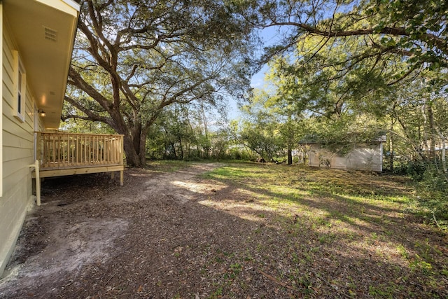 view of yard featuring an outbuilding, a wooden deck, and a storage shed