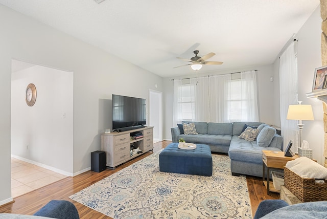 living room with a ceiling fan, light wood-style floors, and baseboards