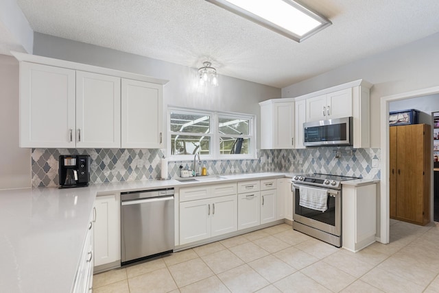 kitchen featuring tasteful backsplash, light countertops, white cabinets, stainless steel appliances, and a sink