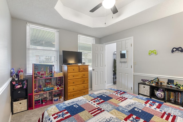 carpeted bedroom with a tray ceiling and ceiling fan