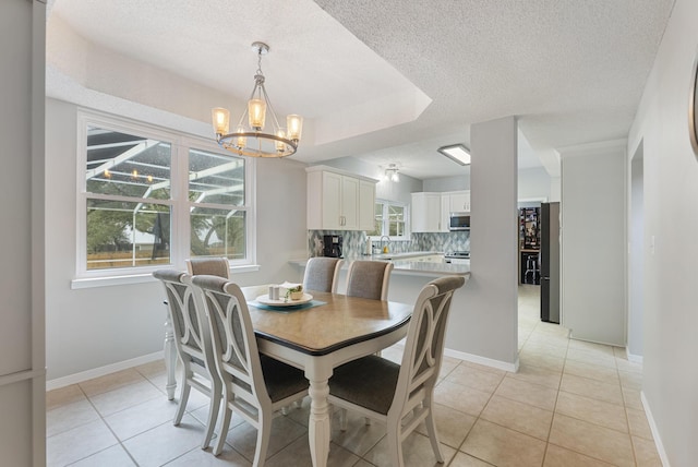 dining room featuring light tile patterned flooring, baseboards, a textured ceiling, and an inviting chandelier