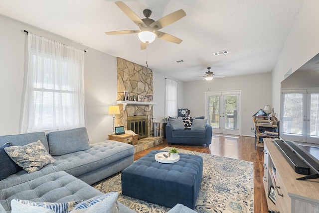 living room with wood finished floors, visible vents, a fireplace, french doors, and a textured ceiling