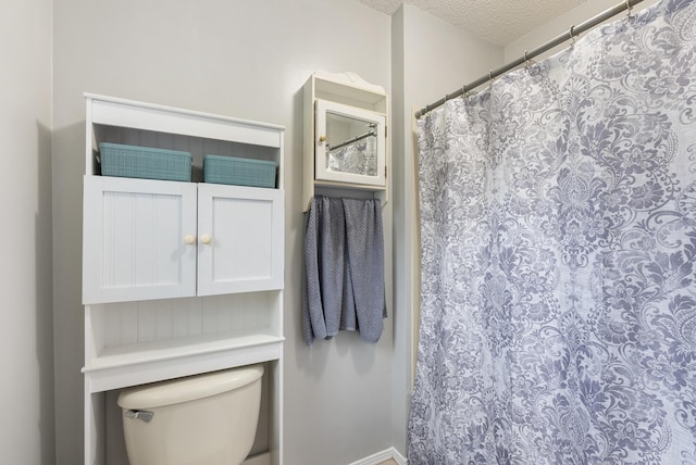 full bath featuring toilet, a textured ceiling, and a shower with shower curtain