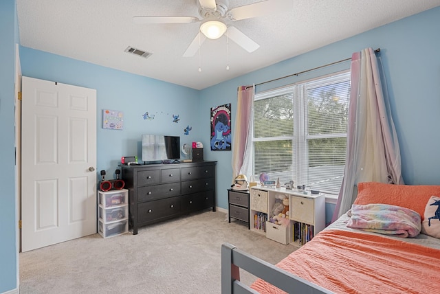 carpeted bedroom featuring visible vents, a textured ceiling, and a ceiling fan