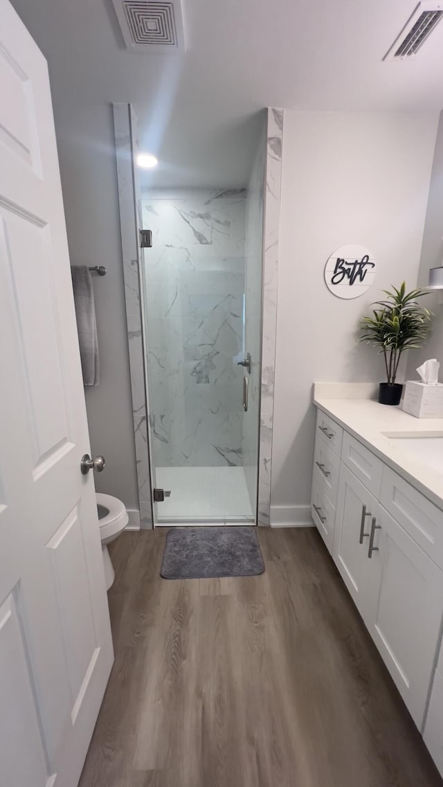 bathroom with a marble finish shower, visible vents, and wood finished floors