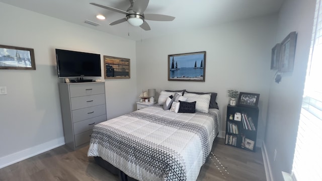 bedroom featuring visible vents, baseboards, dark wood finished floors, and a ceiling fan