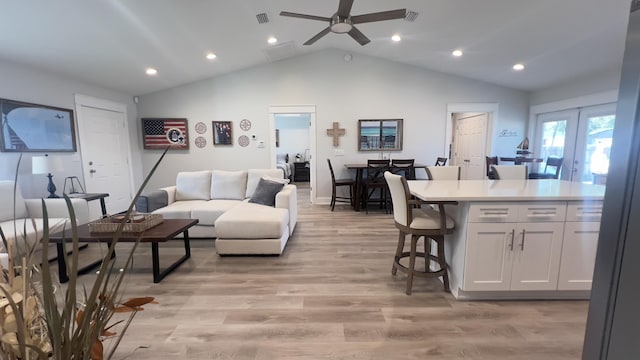 living room with lofted ceiling, a ceiling fan, visible vents, light wood-style floors, and french doors